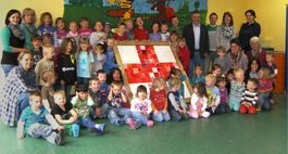 Kinder, Erzieherinnen und DRK-Vertreter als Gruppe zusammen mit selbst erstellter Collage