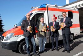 Trostpenderbären in den Händen von 4 Männern vor einem Rettungswagen